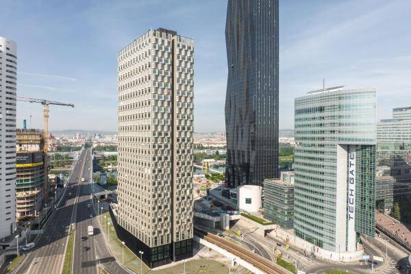 Luftaufnahme des Towers aus anderer Richtung. Rechts im Bild sind zwei weitere Hochhäuser zu sehen. Links vom Gebäude verläuft eine sechsspurige Straße über die Donau Richtung Wiener-Innenstadt. Luftaufnahme des Towers aus anderer Richtung. Rechts im Bild sind zwei weitere Hochhäuser zu sehen. Links vom Gebäude verläuft eine sechsspurige Straße über die Donau Richtung Wiener-Innenstadt.