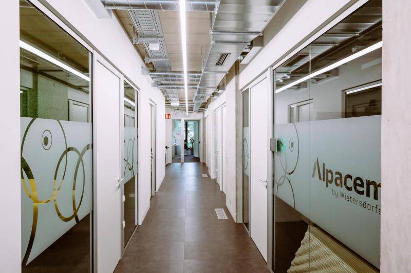 Enger Gang, an dem links und rechts Glaswände zu den Bürorämen sind. Enger Gang, an dem links und rechts Glaswände zu den Bürorämen sind.