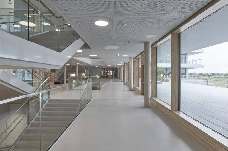 Flur und Treppenhaus. Bodenbelag in Sicht-Estrich, Holzrahen um die Fesnter als Kontrast. Abgehängte, weiße Decken. Flur und Treppenhaus. Bodenbelag in Sicht-Estrich, Holzrahen um die Fesnter als Kontrast. Abgehängte, weiße Decken.