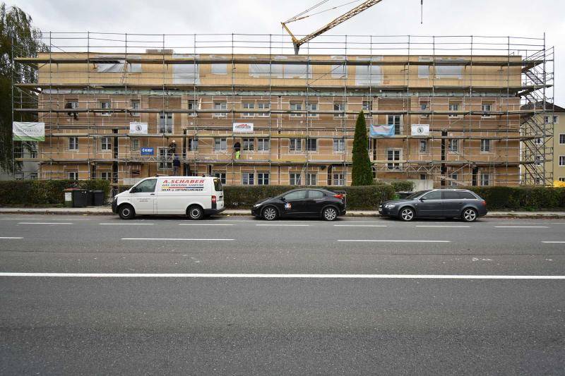 Blick über die Straße auf das Gebäude im Bauzustand. Um das Haus steht Gerüst. Im Hintergrund ist ein Kran zu sehen. Die Fassade ist während dem Bau braun zu erkennen. Blick über die Straße auf das Gebäude im Bauzustand. Um das Haus steht Gerüst. Im Hintergrund ist ein Kran zu sehen. Die Fassade ist während dem Bau braun zu erkennen.