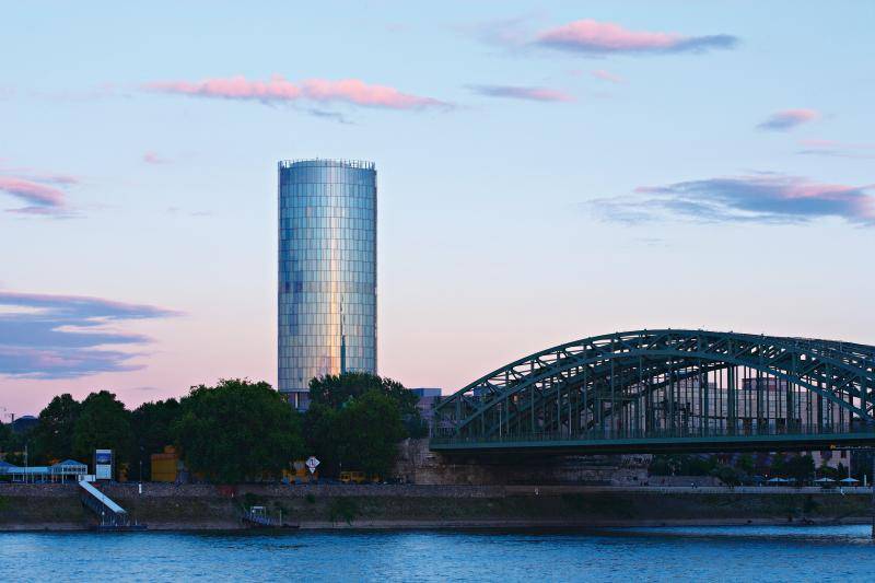Das Gebäude neben der bekannten Einsenbahnbrücke über dem Rhein. Der Glasturm wirkt wie angestrahlt durch die untergehende Sonne. Das Gebäude neben der bekannten Einsenbahnbrücke über dem Rhein. Der Glasturm wirkt wie angestrahlt durch die untergehende Sonne.